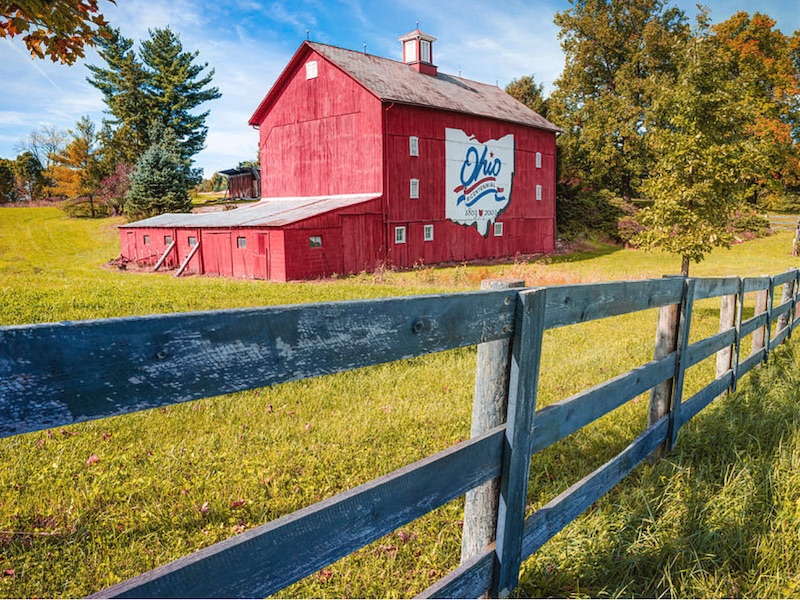 Red barn on a farm with the state outline of Ohio painted on the side.